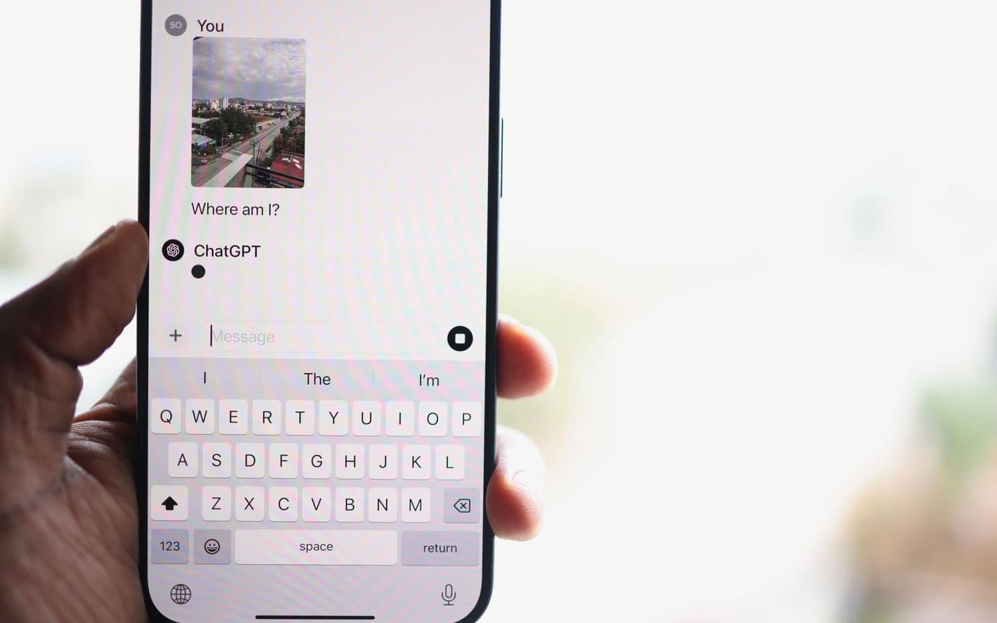 Person hält ein Smartphone mit einem geöffneten Chatfenster einer KI-Anwendung