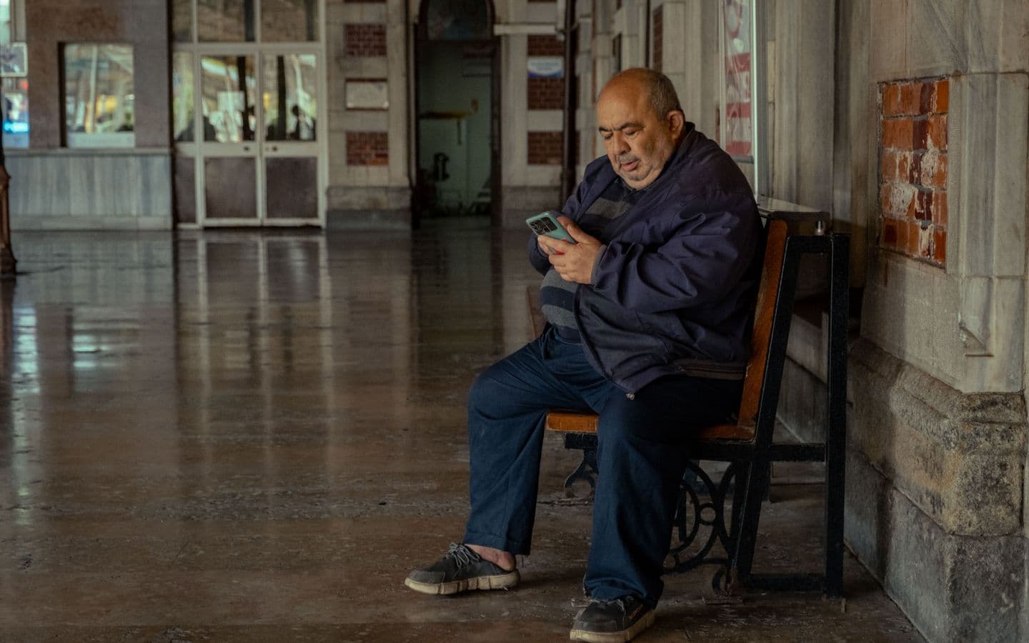 Älterer Mann schaut an einem ruhigen Bahnhof in Istanbul auf sein Handy
