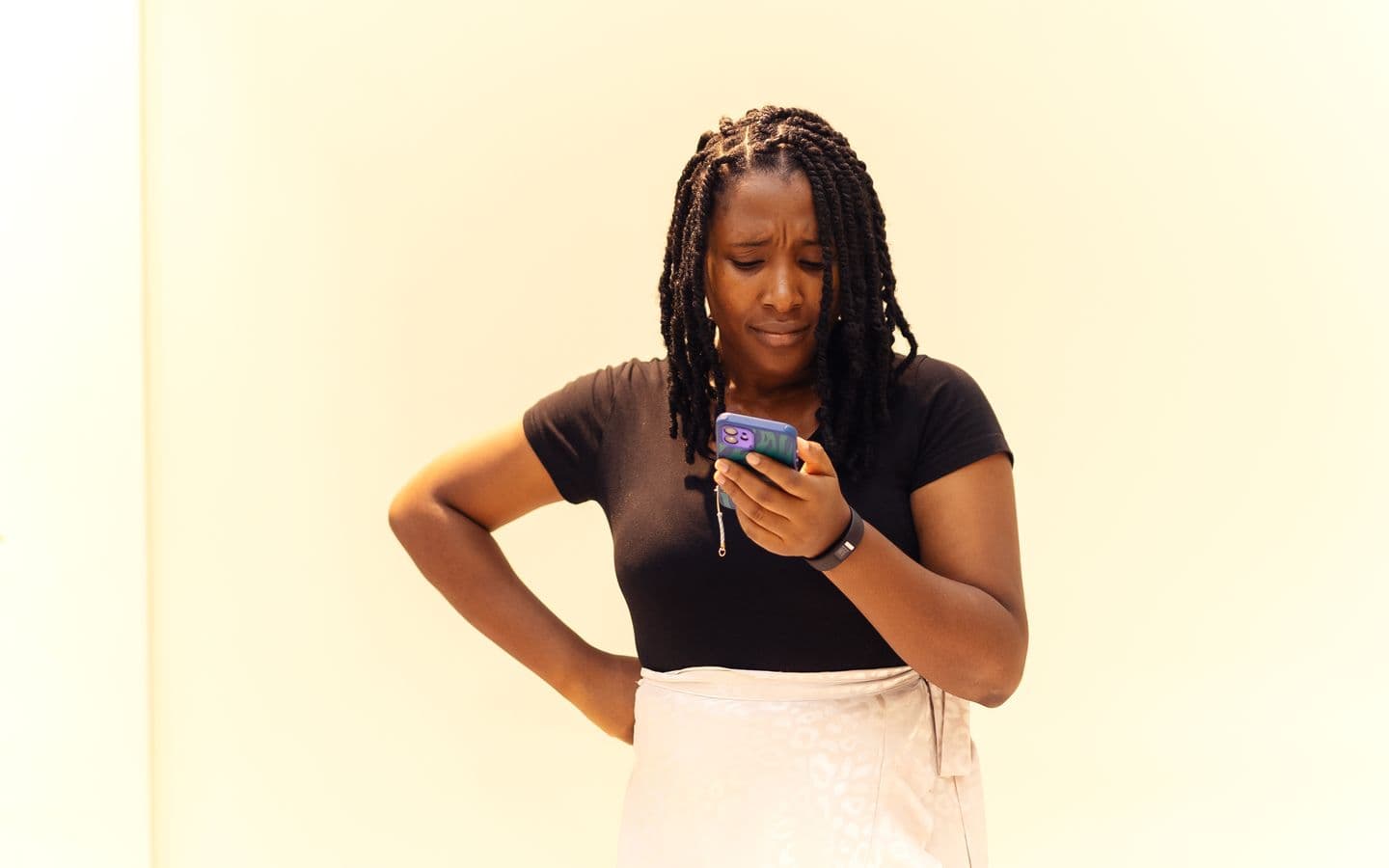 Junge Frau mit Zöpfen schaut in Lagos, Nigeria, auf ihr Handy