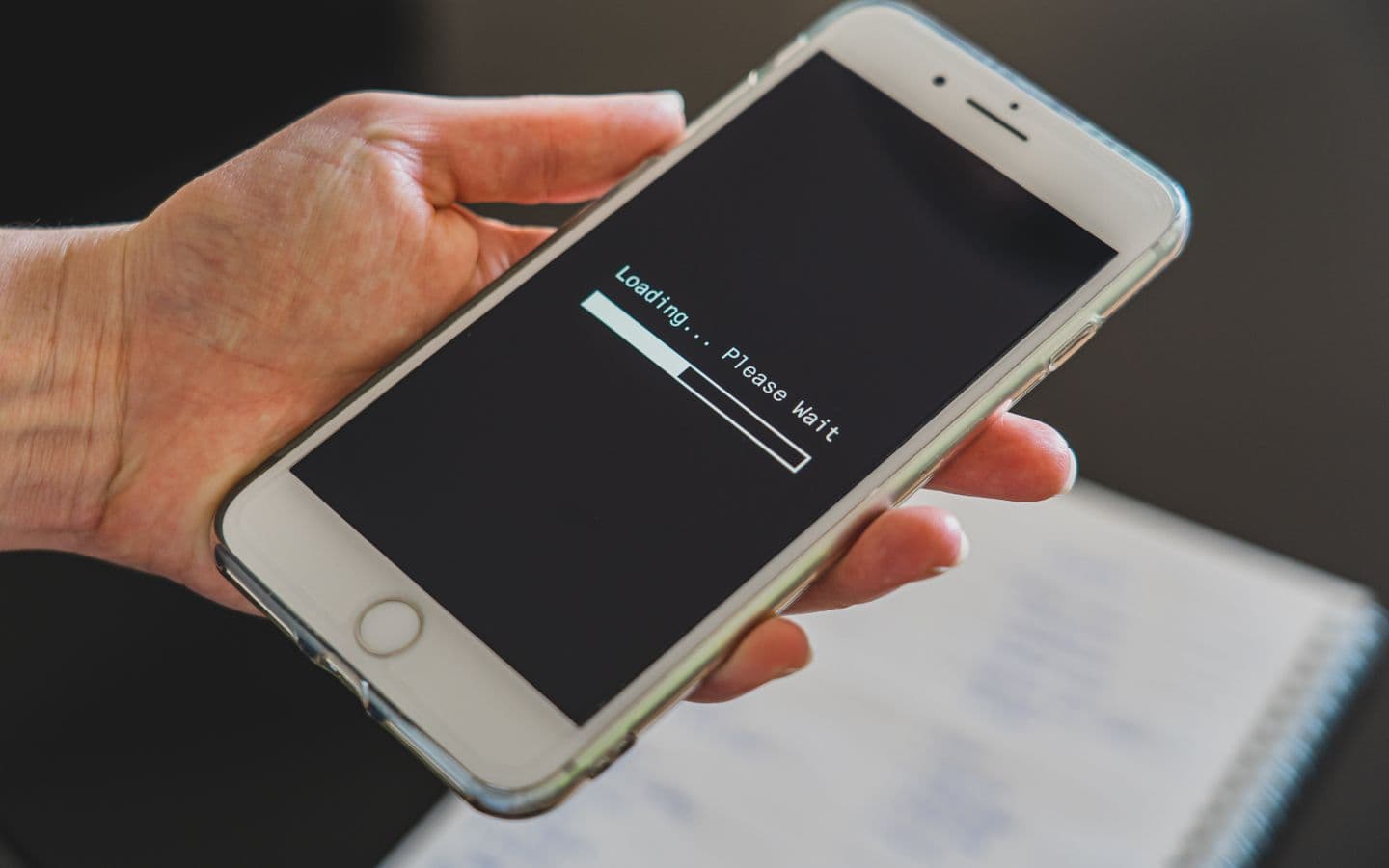 Nahaufnahme einer Hand, die ein Smartphone mit Ladebildschirm hält