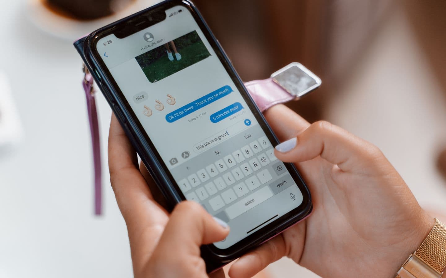 Frau tippt auf dem Smartphone eine Textnachricht mit Emoji
