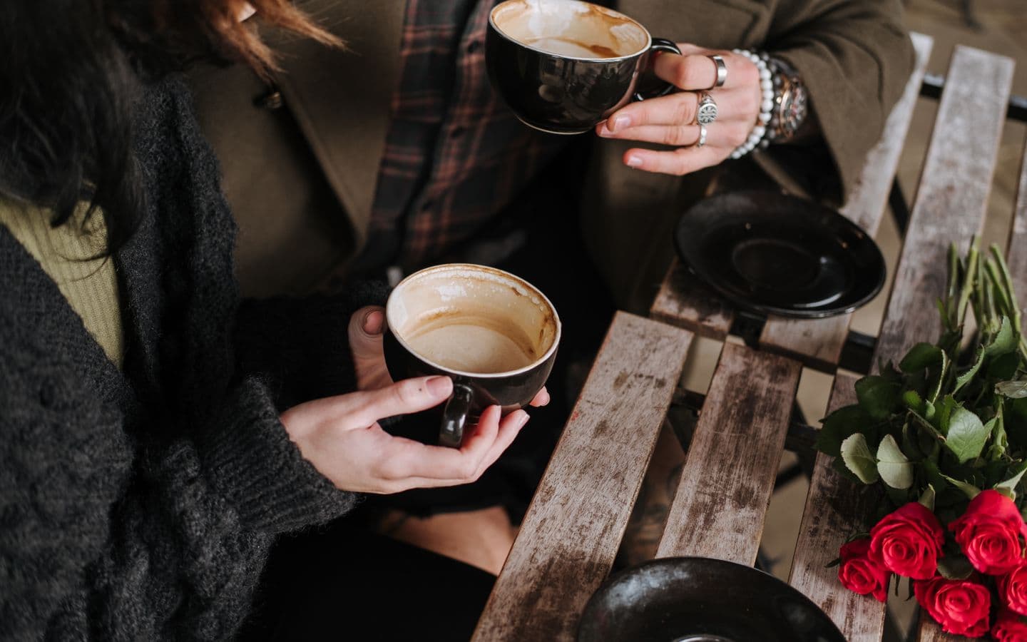 Paar mit Kaffee an einem Cafétisch mit blühenden Blumen, von oben fotografiert