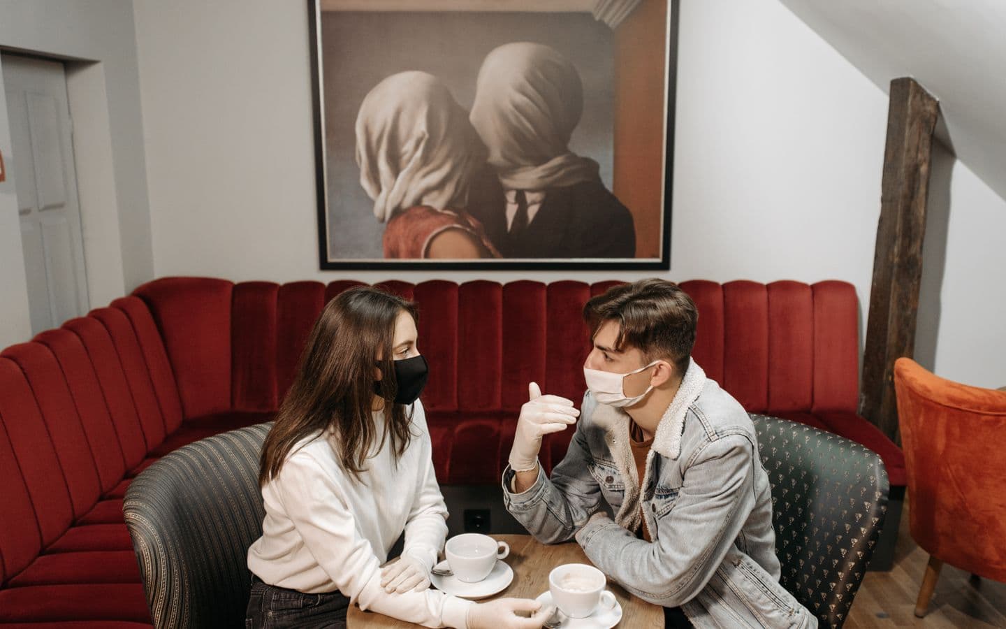 Paar mit Masken trinkt Kaffee in einem gemütlichen Café