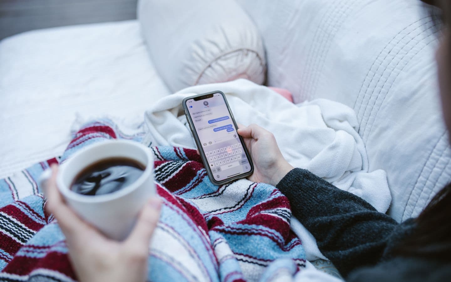 Person entspannt mit Kaffee und Smartphone zu Hause und schreibt eine Nachricht
