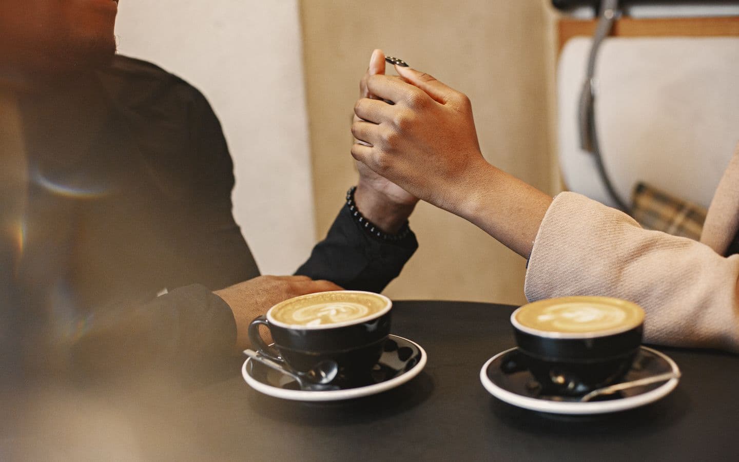 Paar hält beim Kaffee in einem gemütlichen Café Händchen