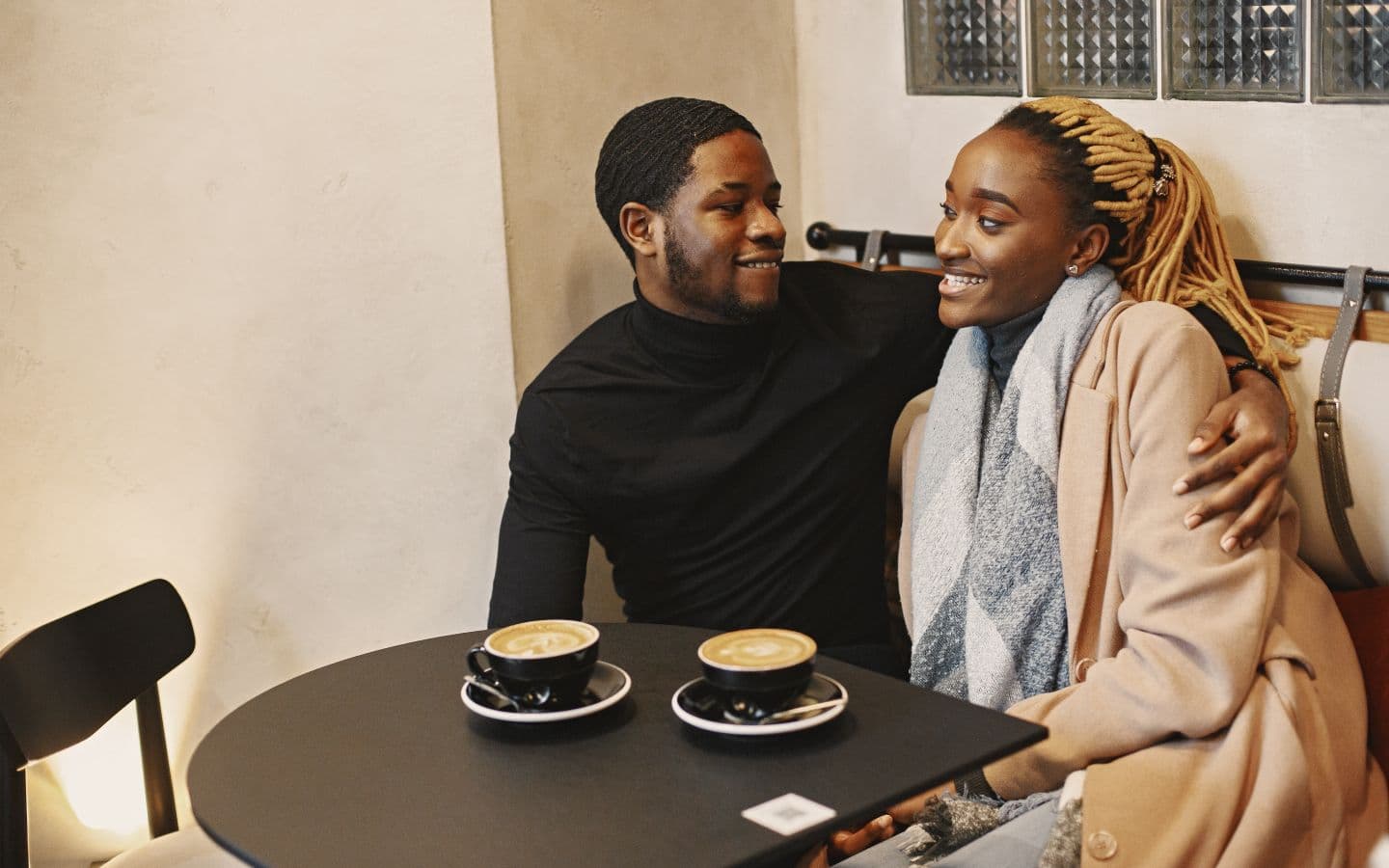 Warmer, gemütlicher Moment eines Paares, das sich bei einem Kaffee im Café anlächelt