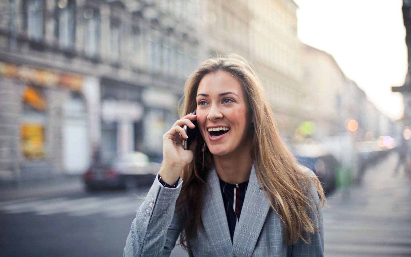 Fröhliche Frau telefoniert beim Gehen auf einer belebten Straße in Budapest
